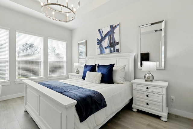 bedroom with baseboards, a chandelier, and light wood-style floors