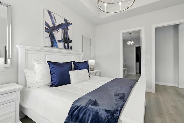 bedroom with a chandelier, light wood-style floors, connected bathroom, and baseboards