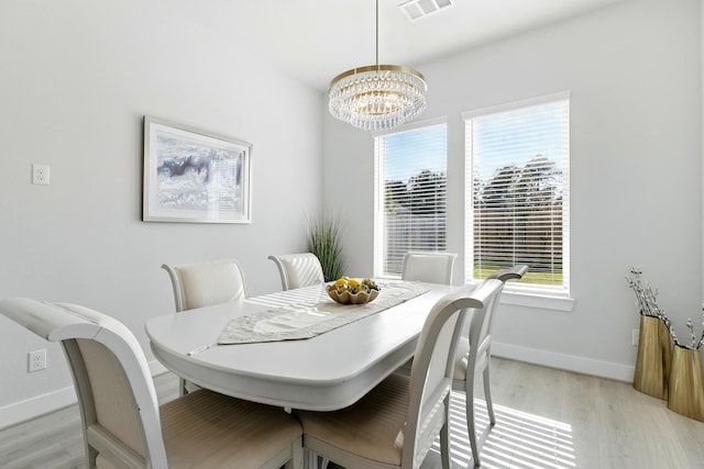 dining space featuring light wood-style flooring, a chandelier, plenty of natural light, and baseboards