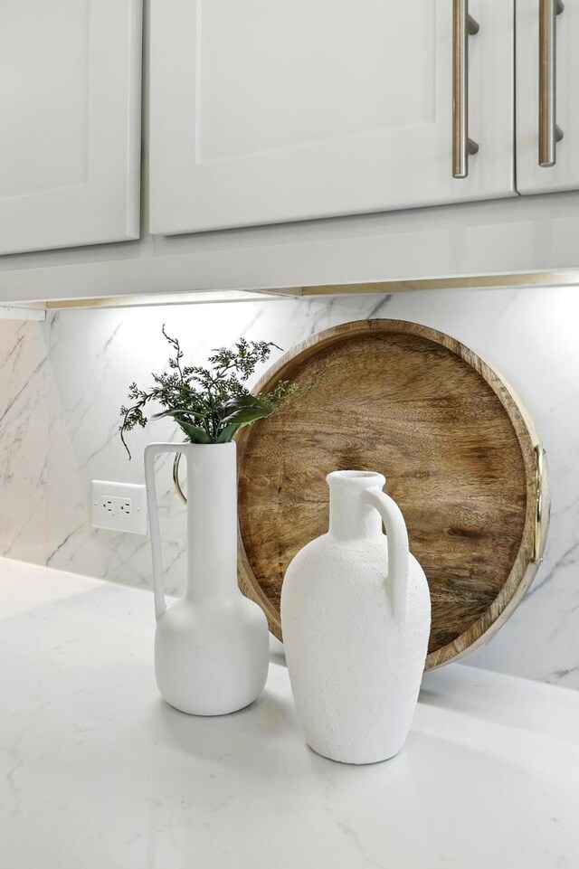 kitchen view of tasteful backsplash, light countertops, and white cabinetry