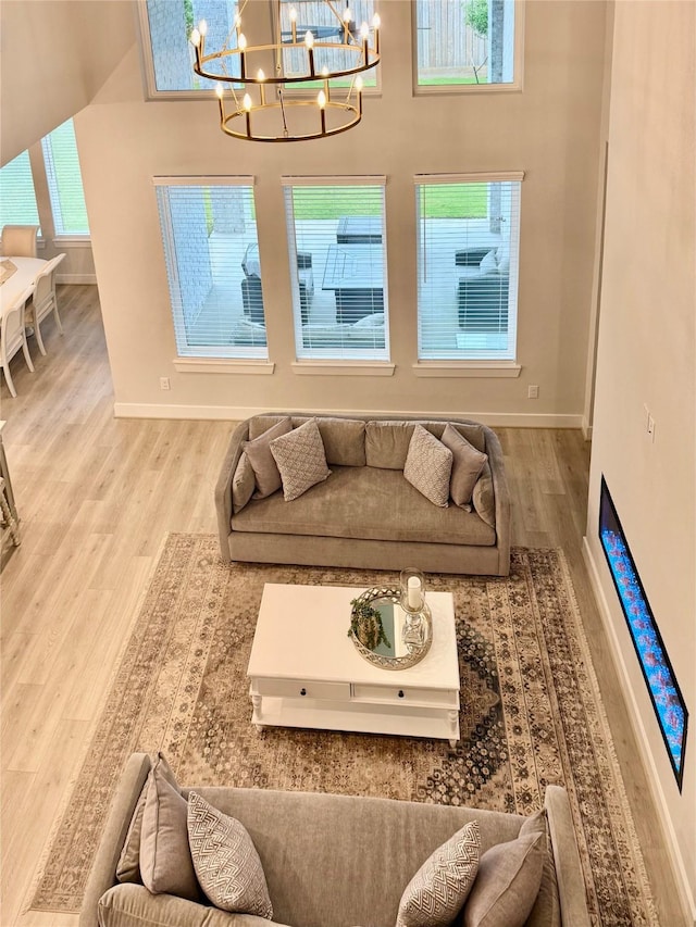 living area featuring a chandelier, wood finished floors, and baseboards
