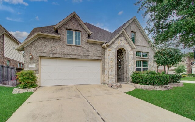 view of front of property featuring concrete driveway, a garage, roof with shingles, brick siding, and stone siding