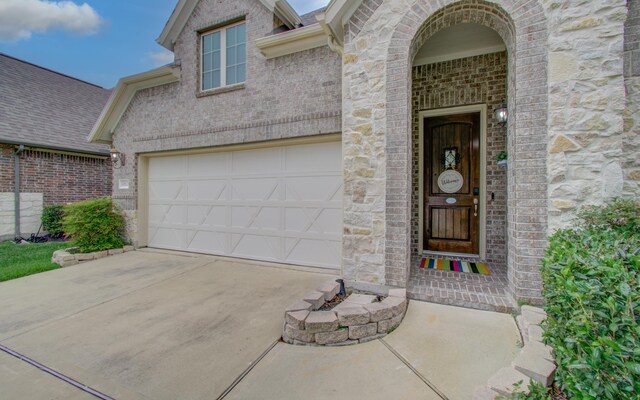 property entrance featuring concrete driveway and brick siding