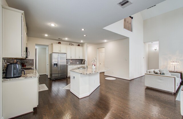 kitchen featuring appliances with stainless steel finishes, a sink, backsplash, dark wood-style flooring, and white cabinets