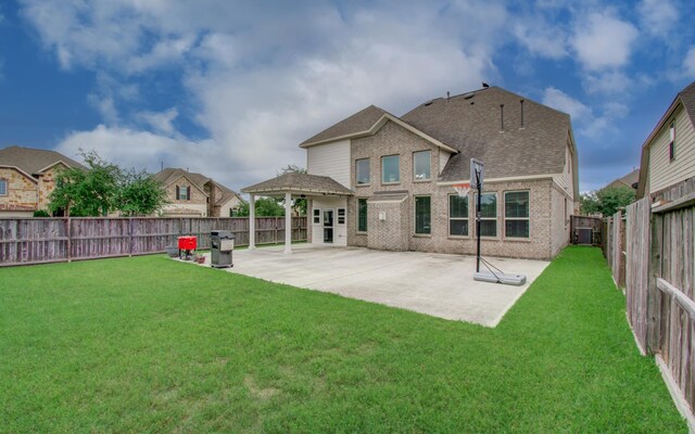 back of house with brick siding, a patio area, and roof with shingles
