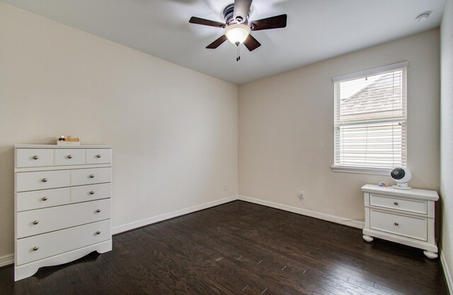 unfurnished bedroom with dark wood finished floors, baseboards, and a ceiling fan