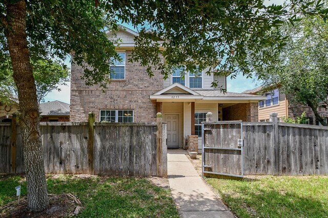 view of front of home featuring brick siding and a gate