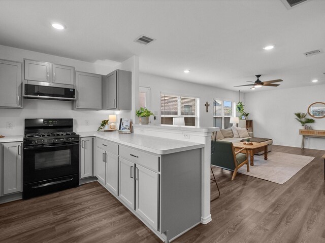 kitchen with black gas stove, stainless steel microwave, gray cabinetry, a peninsula, and light countertops