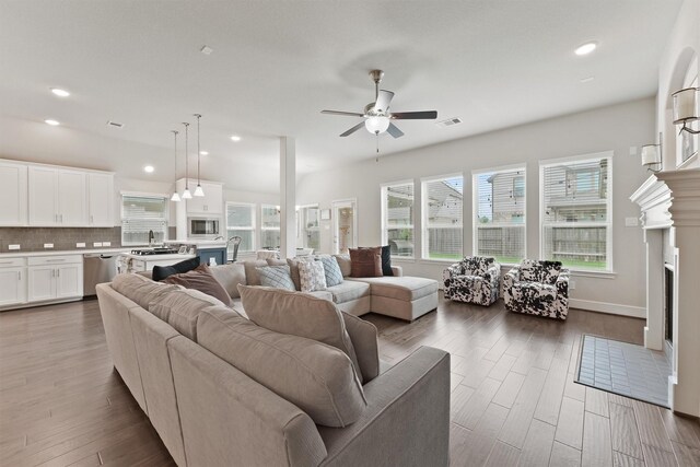 living area with a fireplace, a ceiling fan, healthy amount of natural light, dark wood-style flooring, and recessed lighting