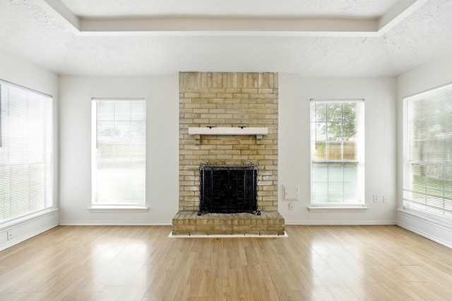 24011 Lone Elm Dr, Spring, TX 77373 - unfurnished living room with a textured ceiling, wood finished floors, a brick fireplace, and baseboards