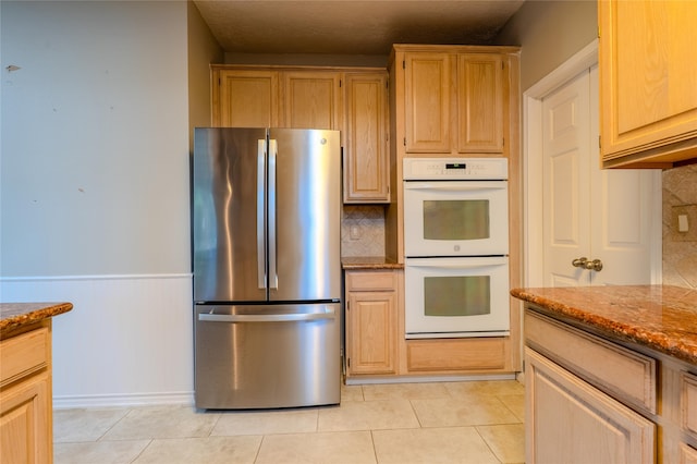 16526 Battlecreek Dr, Houston, TX 77095 - kitchen featuring freestanding refrigerator, white double oven, stone countertops, tasteful backsplash, and a wainscoted wall