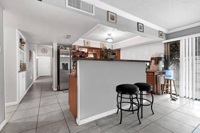 kitchen with stainless steel fridge with ice dispenser, light tile patterned flooring, baseboards, crown molding, and a textured ceiling