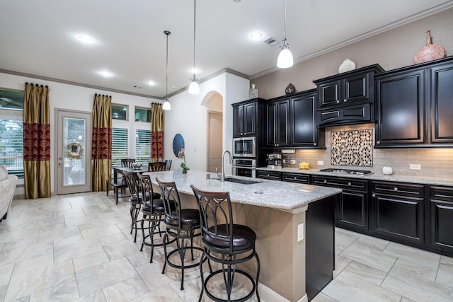 22903 Laburname Ct, Tomball, TX 77375 - kitchen with arched walkways, appliances with stainless steel finishes, dark cabinets, a sink, and crown molding