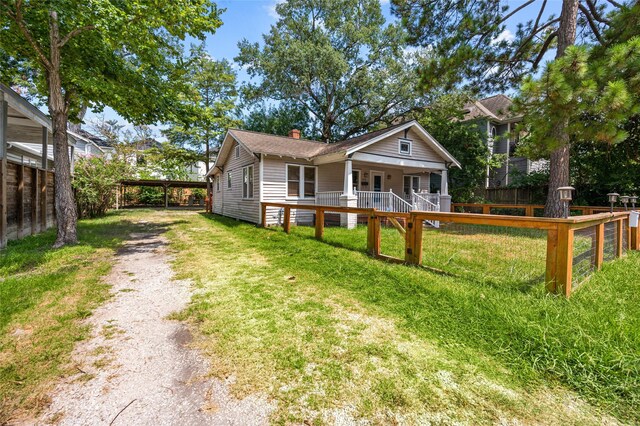 view of front of house featuring a chimney, driveway, a detached carport, and a porch