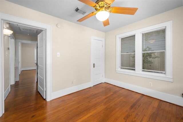 unfurnished bedroom with attic access, wood finished floors, baseboards, and a ceiling fan