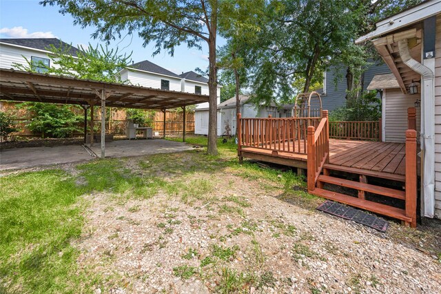 fenced backyard featuring a wooden deck, a shed, a patio, and an outdoor structure