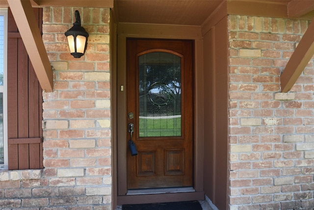view of exterior entry featuring brick siding