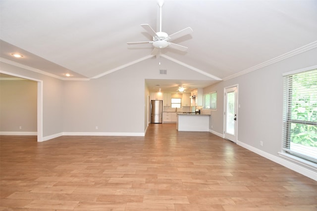 unfurnished living room with ornamental molding, a ceiling fan, baseboards, healthy amount of natural light, and vaulted ceiling
