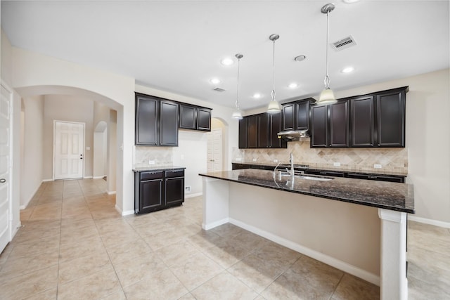 18230 Russett Green Dr, Tomball, TX 77377 - kitchen featuring arched walkways, a sink, dark stone counters, decorative backsplash, and light tile patterned flooring