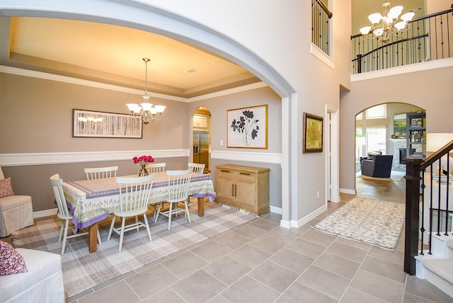 5006 Isidore Ln, Missouri City, TX 77459 - dining room with a chandelier, arched walkways, a tray ceiling, stairs, and baseboards