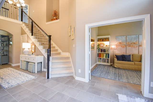 5006 Isidore Ln, Missouri City, TX 77459 - tiled foyer entrance with a chandelier, a high ceiling, stairs, baseboards, and arched walkways