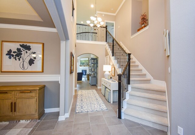 5006 Isidore Ln, Missouri City, TX 77459 - entrance foyer with arched walkways, a chandelier, light tile patterned floors, stairway, and ornamental molding