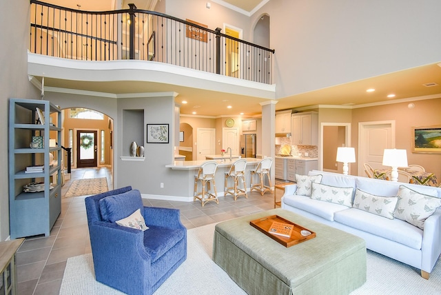 5006 Isidore Ln, Missouri City, TX 77459 - living room featuring crown molding, a towering ceiling, tile patterned floors, arched walkways, and baseboards