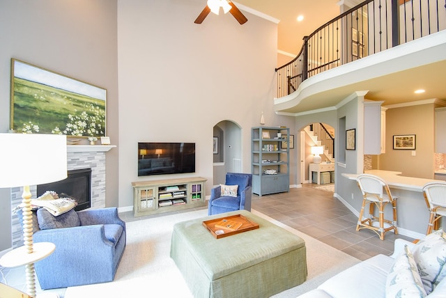 5006 Isidore Ln, Missouri City, TX 77459 - tiled living area with arched walkways, a high ceiling, a tile fireplace, baseboards, and a ceiling fan