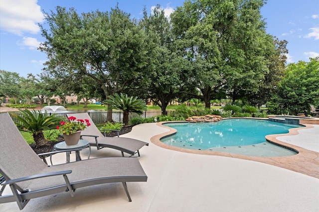 view of swimming pool with a patio area, fence, and a pool with connected hot tub
