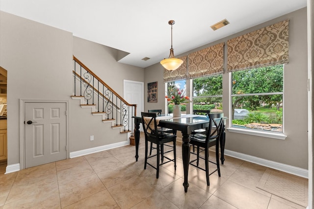 dining space featuring baseboards, light tile patterned floors, and stairway