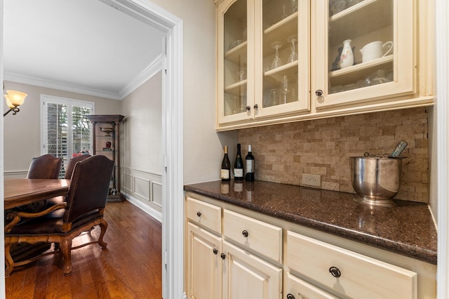 bar with crown molding, dark wood finished floors, decorative backsplash, a wainscoted wall, and a decorative wall