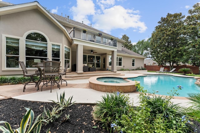 back of property with a balcony, ceiling fan, a patio, and stucco siding