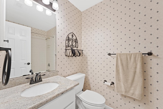 bathroom featuring wallpapered walls, toilet, vanity, and a shower