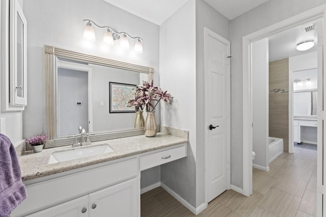 bathroom featuring vanity, bathtub / shower combination, and baseboards