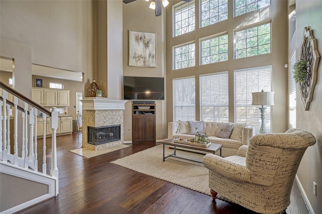 70 Harvest Wind Pl, The Woodlands, TX 77382 - living area featuring a towering ceiling, a ceiling fan, dark wood-style flooring, stairs, and a tiled fireplace