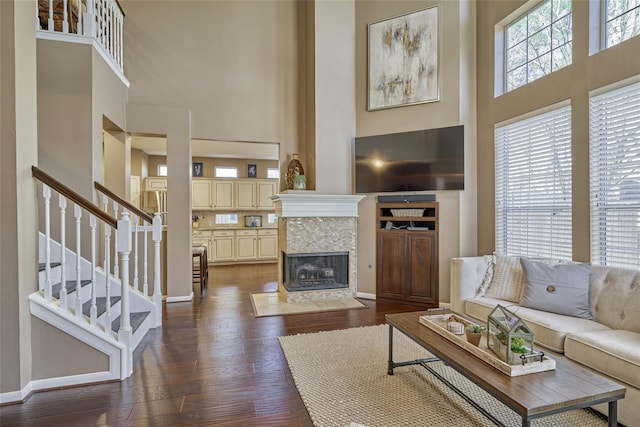 70 Harvest Wind Pl, The Woodlands, TX 77382 - living room featuring a high ceiling, stairs, dark wood-type flooring, baseboards, and a tiled fireplace