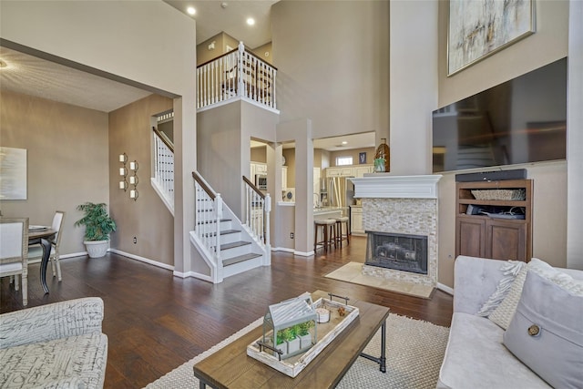 70 Harvest Wind Pl, The Woodlands, TX 77382 - living room featuring stairs, hardwood / wood-style floors, baseboards, a tile fireplace, and a towering ceiling