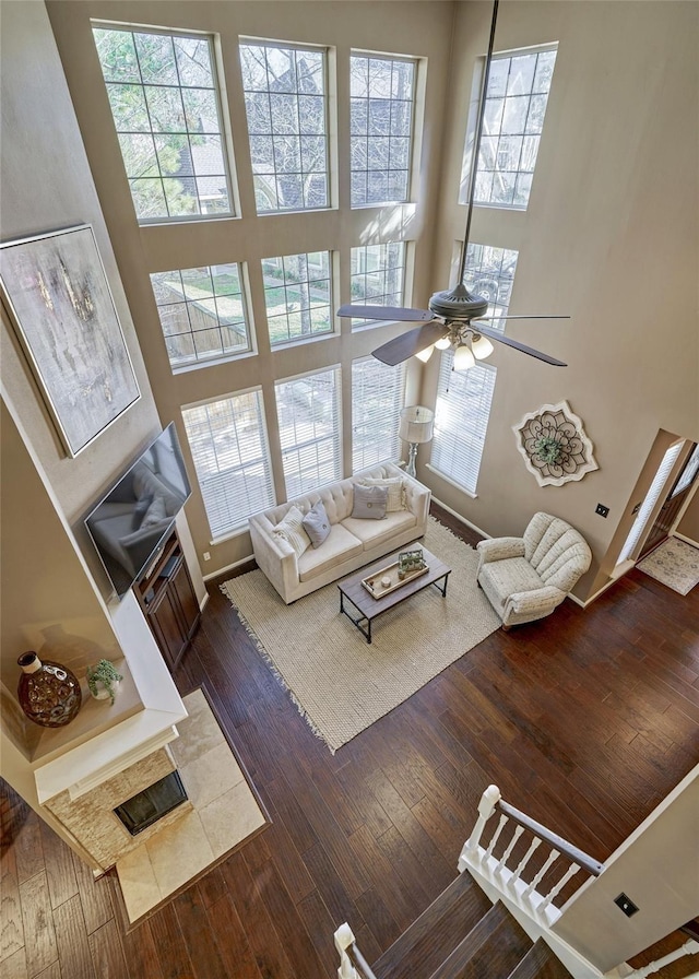 70 Harvest Wind Pl, The Woodlands, TX 77382 - living area featuring dark wood-style floors, a ceiling fan, plenty of natural light, a high ceiling, and baseboards