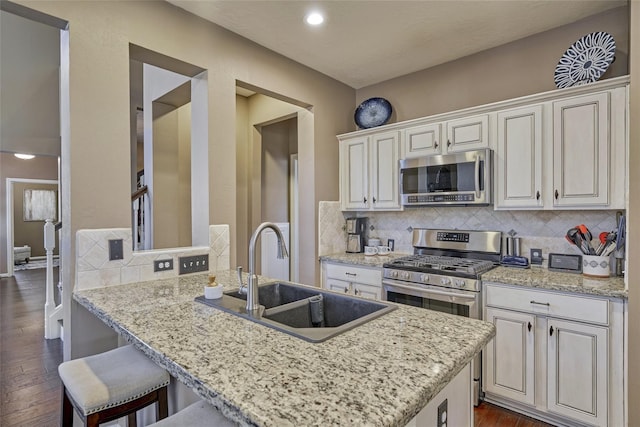 70 Harvest Wind Pl, The Woodlands, TX 77382 - kitchen with appliances with stainless steel finishes, a sink, dark wood-type flooring, backsplash, and a breakfast bar area