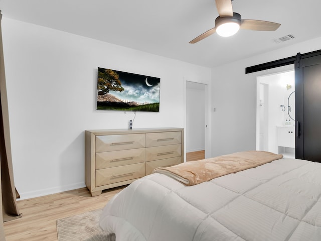 507 Patricia, San Antonio, TX 78216 - bedroom with a barn door, light wood-style floors, baseboards, a ceiling fan, and ensuite bath