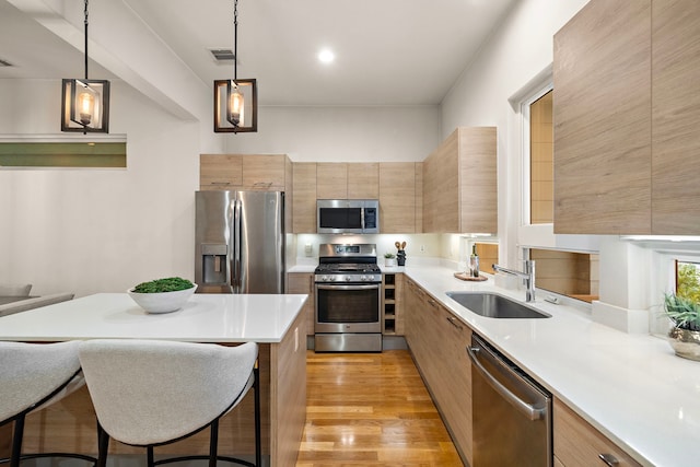 2705 St Emanuel St, Houston, TX 77004 - kitchen with stainless steel appliances, a sink, modern cabinets, light countertops, and hanging light fixtures