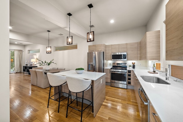 2705 St Emanuel St, Houston, TX 77004 - kitchen with appliances with stainless steel finishes, a sink, a kitchen breakfast bar, light countertops, and a kitchen island