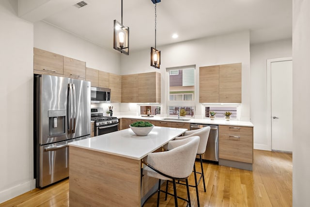 2705 St Emanuel St, Houston, TX 77004 - kitchen with stainless steel appliances, a kitchen island, a sink, a breakfast bar area, and light countertops