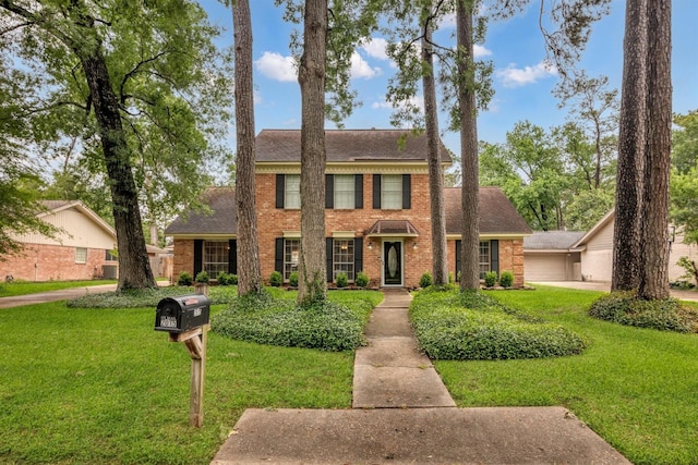 colonial house with brick siding, a front lawn, and roof with shingles