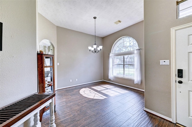 923 Garrett Dr, Magnolia, TX 77354 - entryway with dark wood-style floors, a chandelier, baseboards, a textured wall, and arched walkways