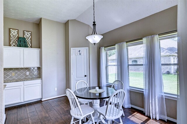 923 Garrett Dr, Magnolia, TX 77354 - dining room featuring dark wood-style floors, lofted ceiling, baseboards, and a textured ceiling