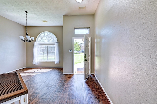923 Garrett Dr, Magnolia, TX 77354 - foyer entrance featuring dark wood-type flooring, a chandelier, baseboards, a textured wall, and a textured ceiling