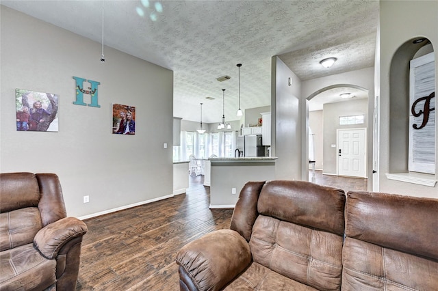 923 Garrett Dr, Magnolia, TX 77354 - living room with arched walkways, dark wood finished floors, baseboards, and a textured ceiling