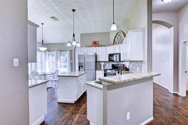 923 Garrett Dr, Magnolia, TX 77354 - kitchen featuring appliances with stainless steel finishes, a textured ceiling, arched walkways, a center island, and dark wood-style floors