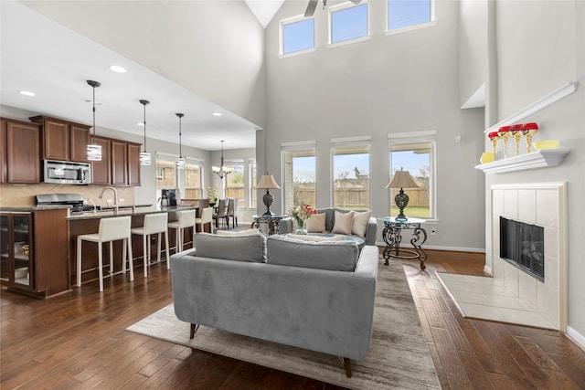 22726 Little Blue Stem Dr, Tomball, TX 77375 - living room featuring baseboards, dark wood-style flooring, a tile fireplace, and a high ceiling